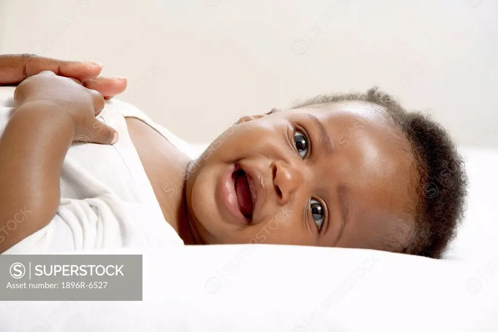 Baby boy lying on his back smiling. Cape Town, Western Cape Province, South Africa