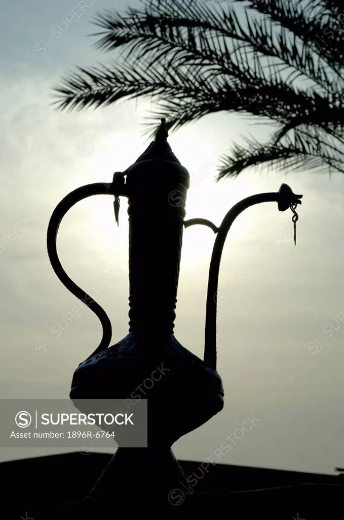 Low angle view of silhouetted middle eastern tea pot with palm in the background, Dubai, UAE