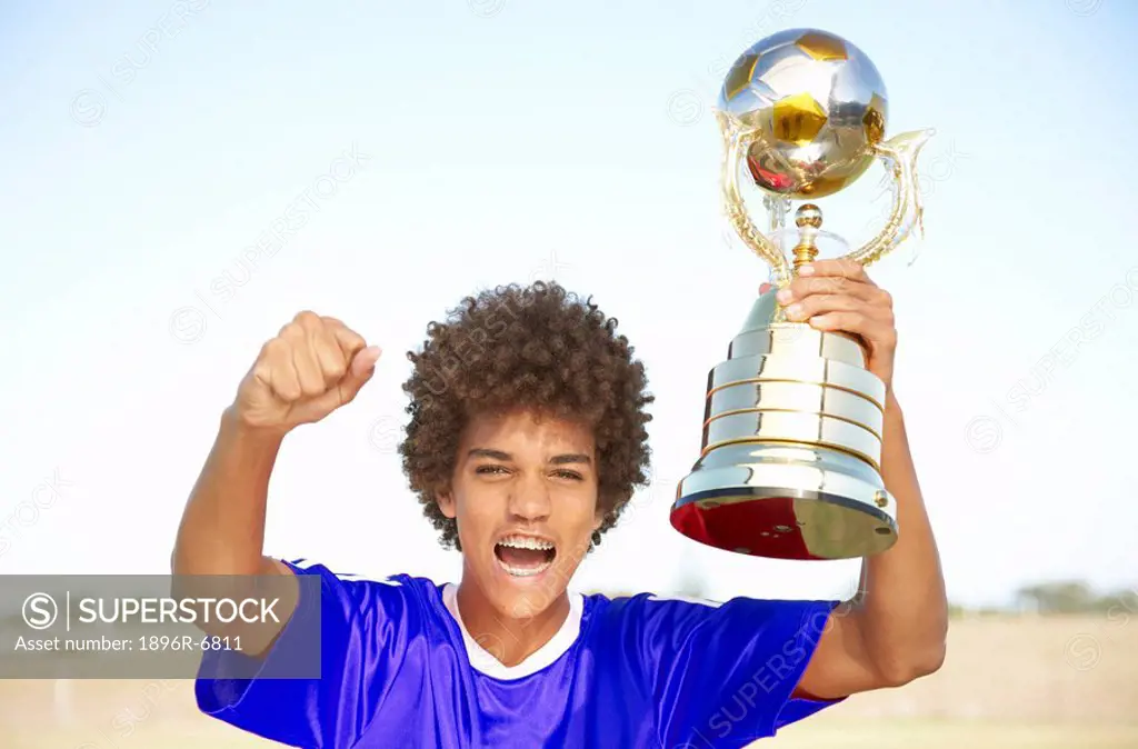 Soccer player holding up winning trophy with pride. Cape Town, Western Cape Province, South Africa
