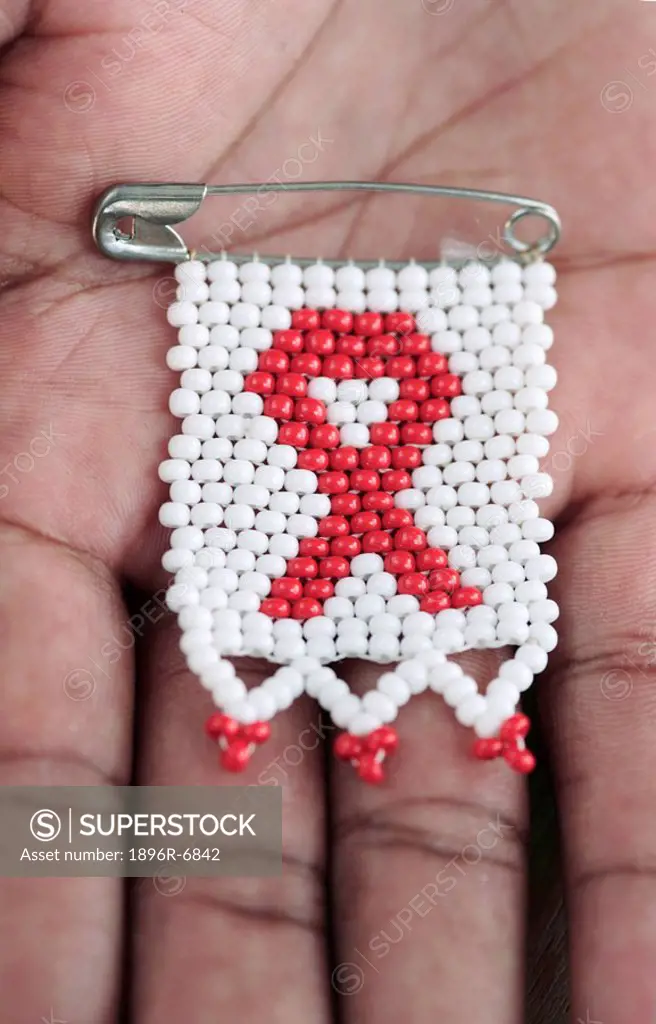 Beaded AIDS ribbon badge on a hand. Grahamstown, Eastern Cape Province, South Africa