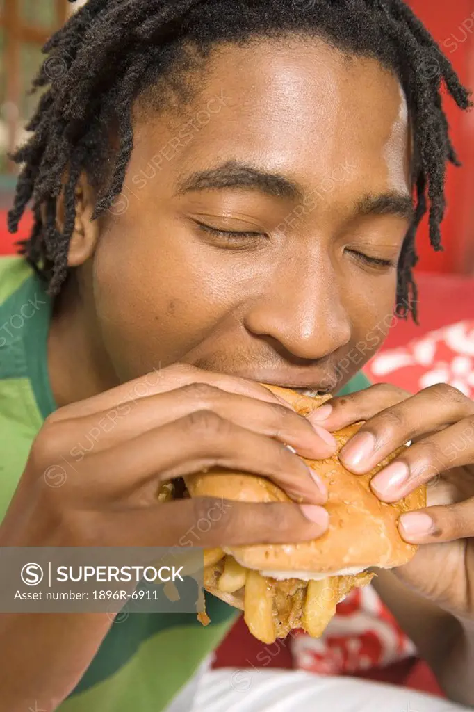 South African teen culture _ Young man taking a bite of a burger.