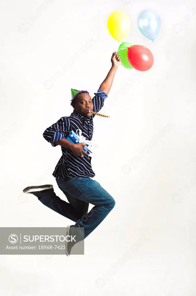 A man leaping with joy carrying a gift and balloons against a white background, Johannesburg, Gauteng Province, South Africa