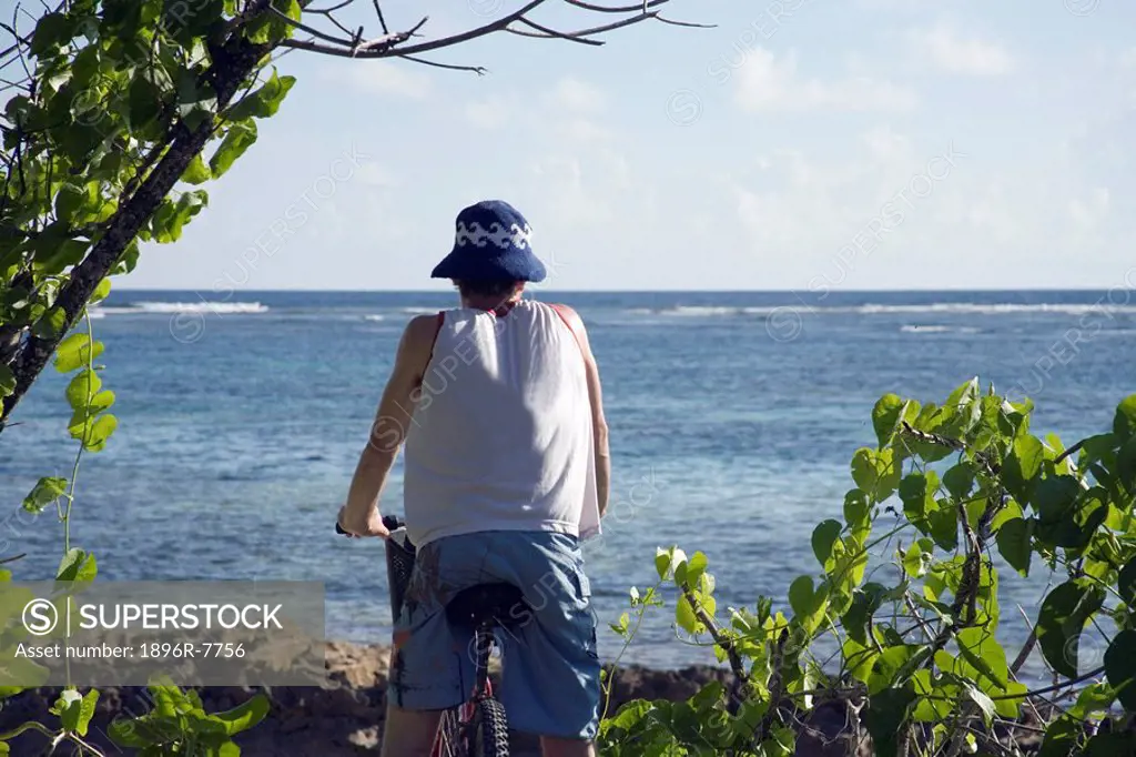 Young man with bicycle alongside beach, Seychelles