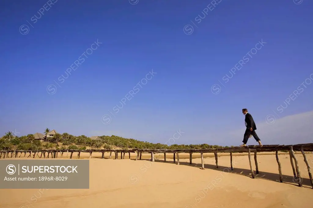 Businessman on raised boardwalk above beach, Lamu Island, Kenya