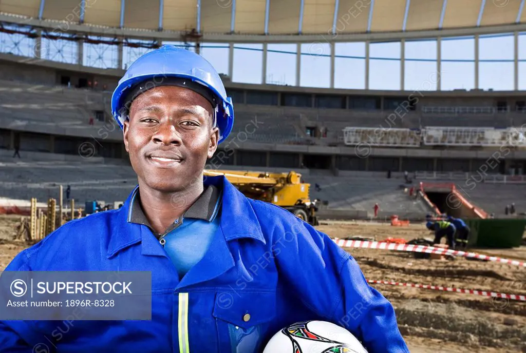 Construction worker with fooballand in front of construction work, Moses Mabhida Stadium, Durban, KwaZului_Natal Province, South Africa