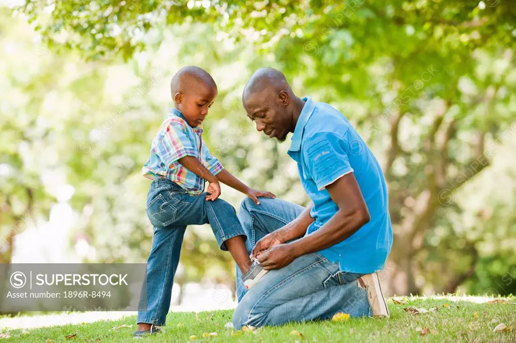 Father tying shoelace for son 4_5 in garden, Johannesburg, Gauteng Province, South Africa