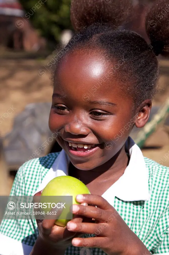 Smiling schoolgirl holding an apple, KwaZulu Natal Province, South Africa