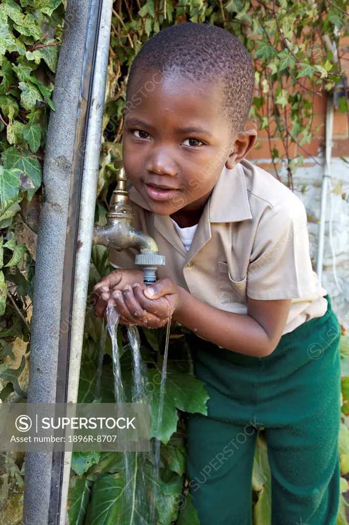 Young schoolboy drinking water from a tap, KwaZulu Natal Province, South Africa
