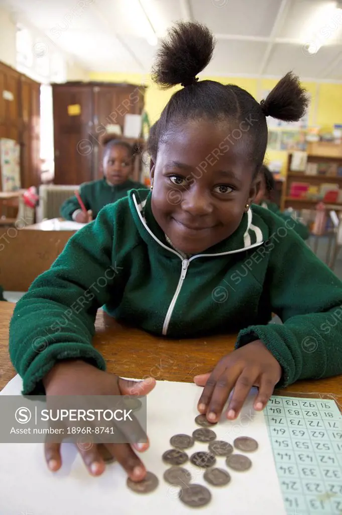Portrait of a schoolgirl smiling as she counts coins, KwaZulu Natal Province, South Africa