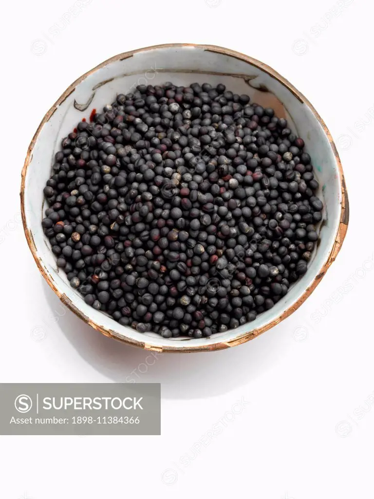 A bowl of black mustard seed on a white background