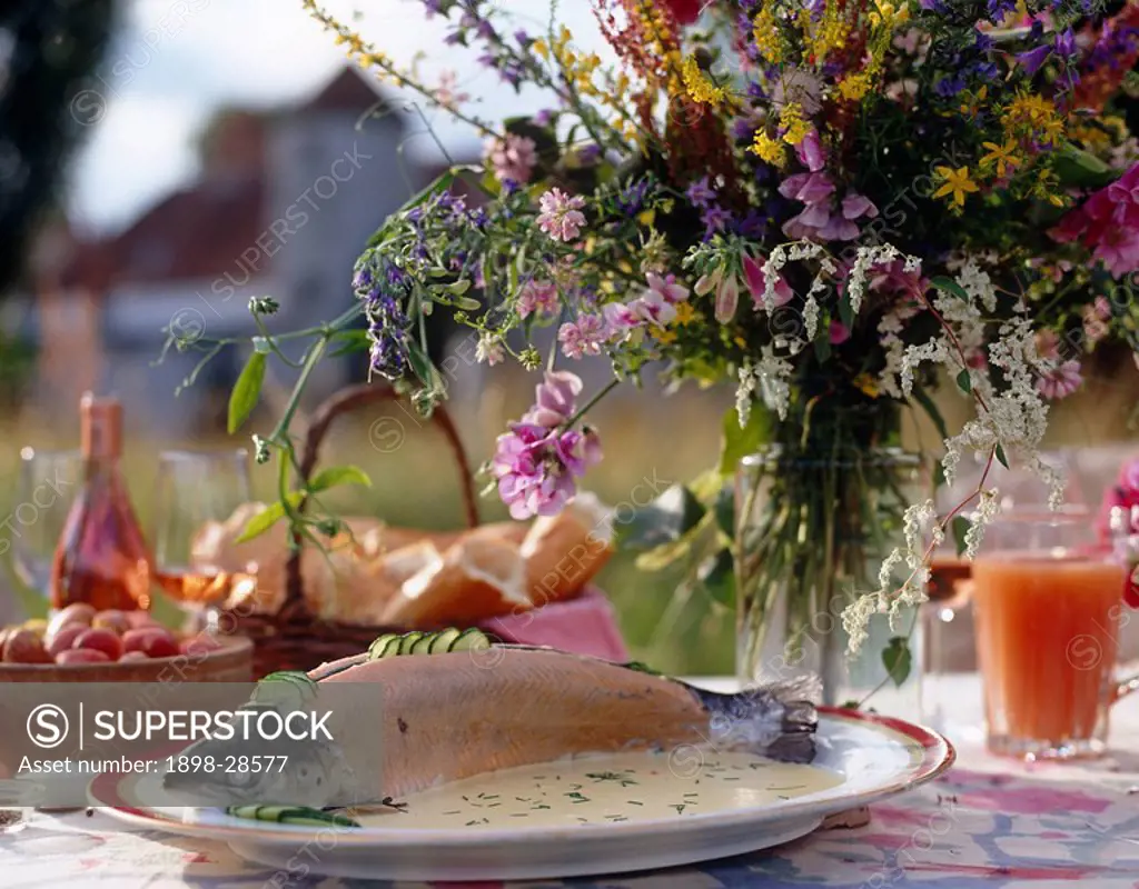 Al fresco food with salmon dish and arrangement of summer flowers