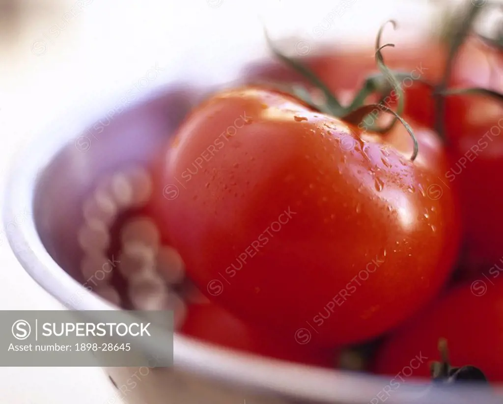 A detail of ripe, red tomatoes in a bowl.