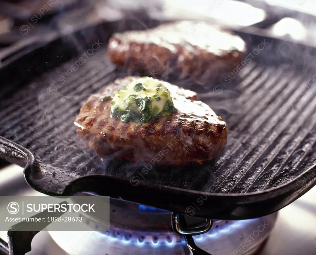 Fillet steak cooking in griddle pan on gas hob.