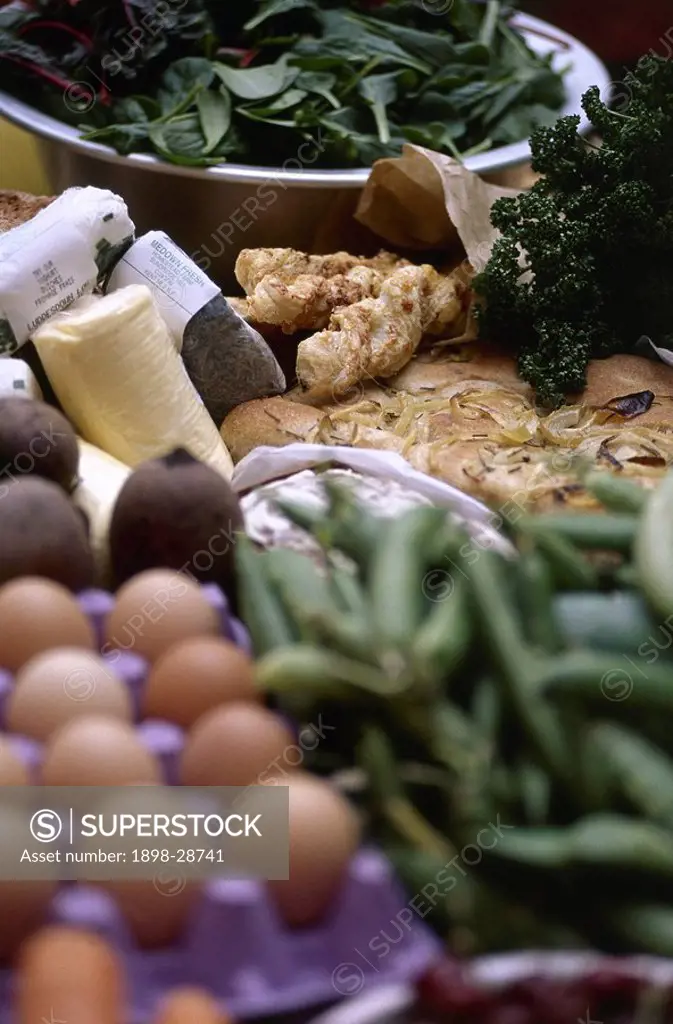 Fresh vegetables, eggs, and cheese, laid out on a table.