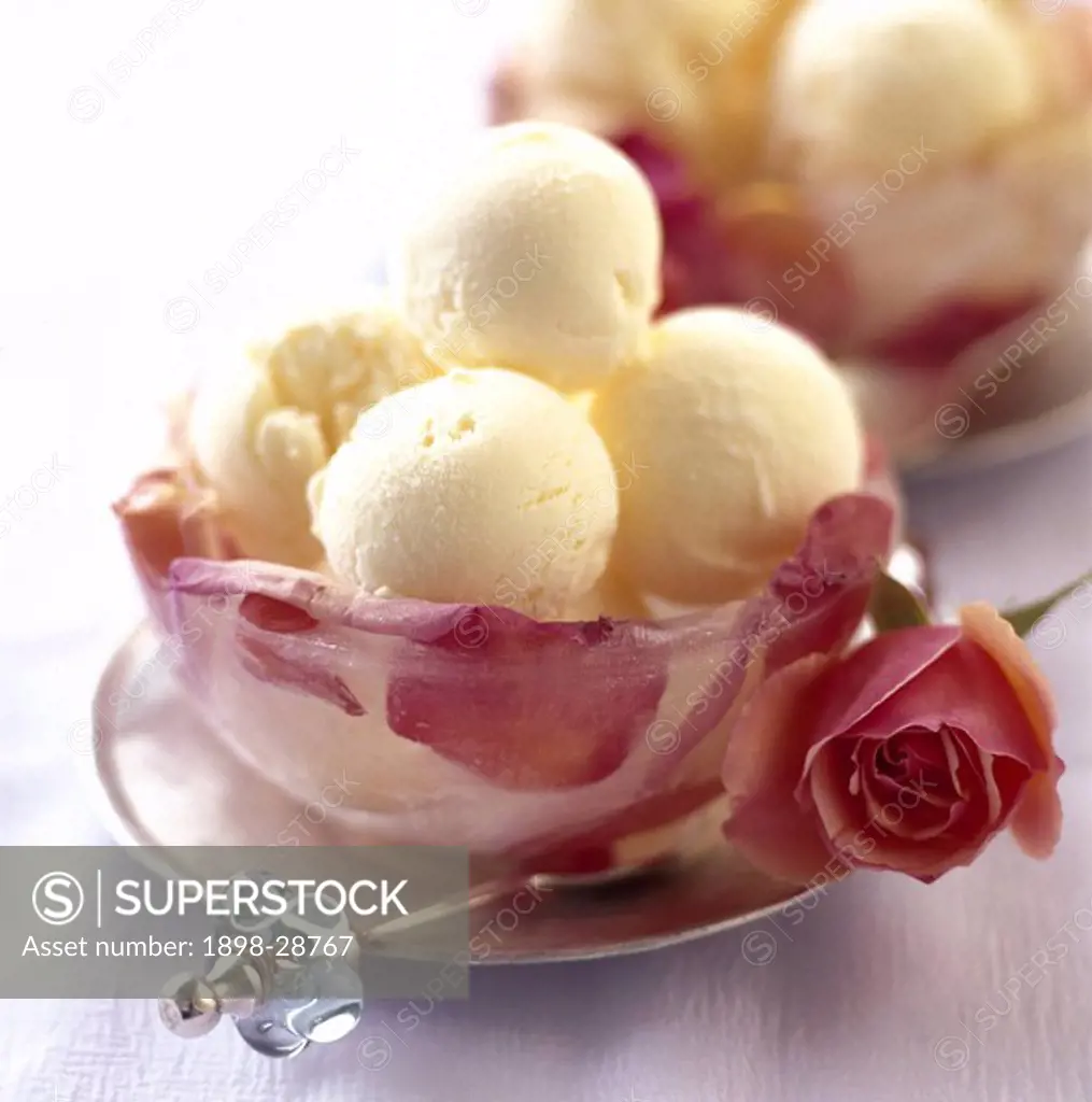 Scoops of rosewater ice cream in an ice bowl with a rose garnish.