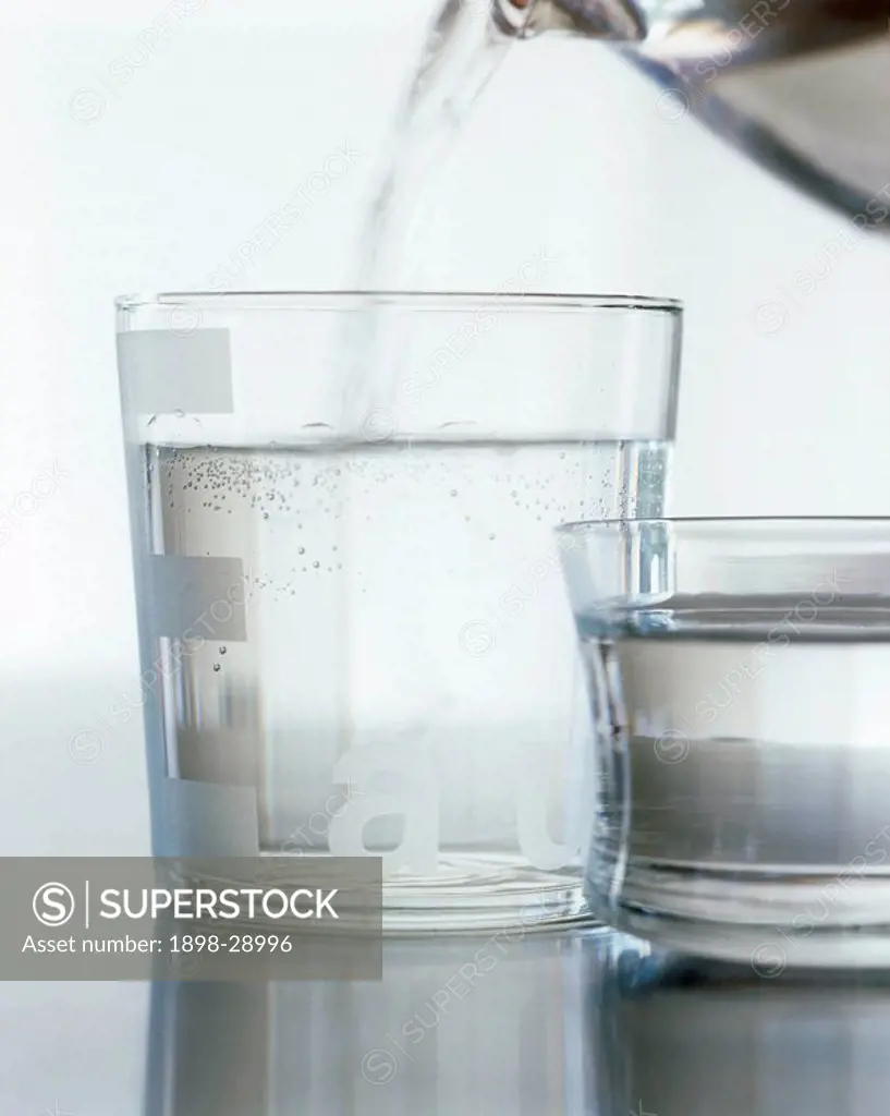 Two glasses of water with one being filled from a jug