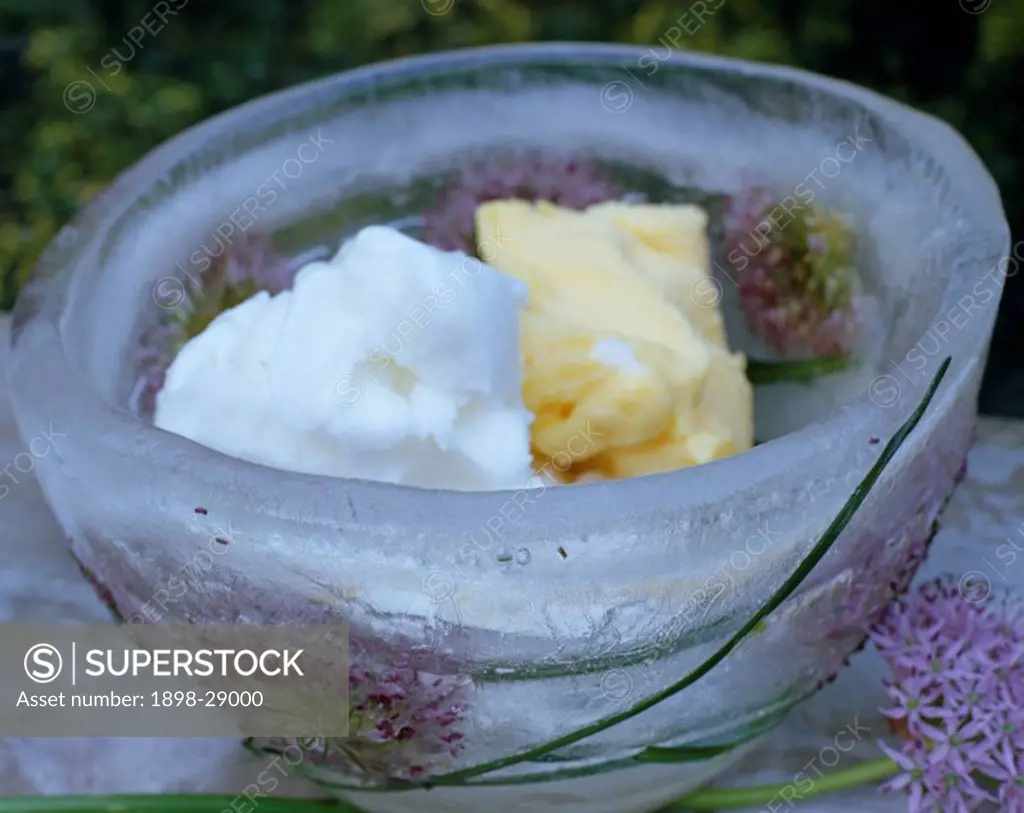 Ice bowl with frozen flowers filled with ice cream on sheet of ice