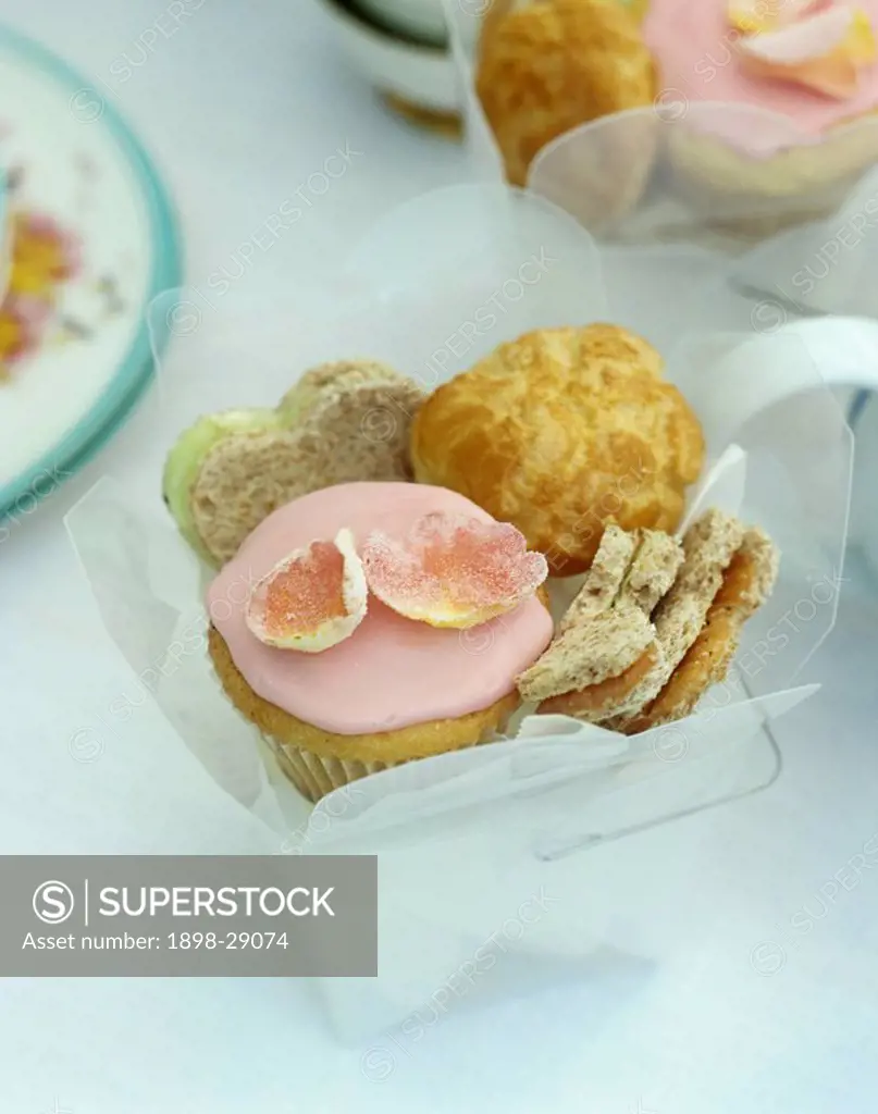 Close up of small container of heart shaped sandwiches and iced cake.