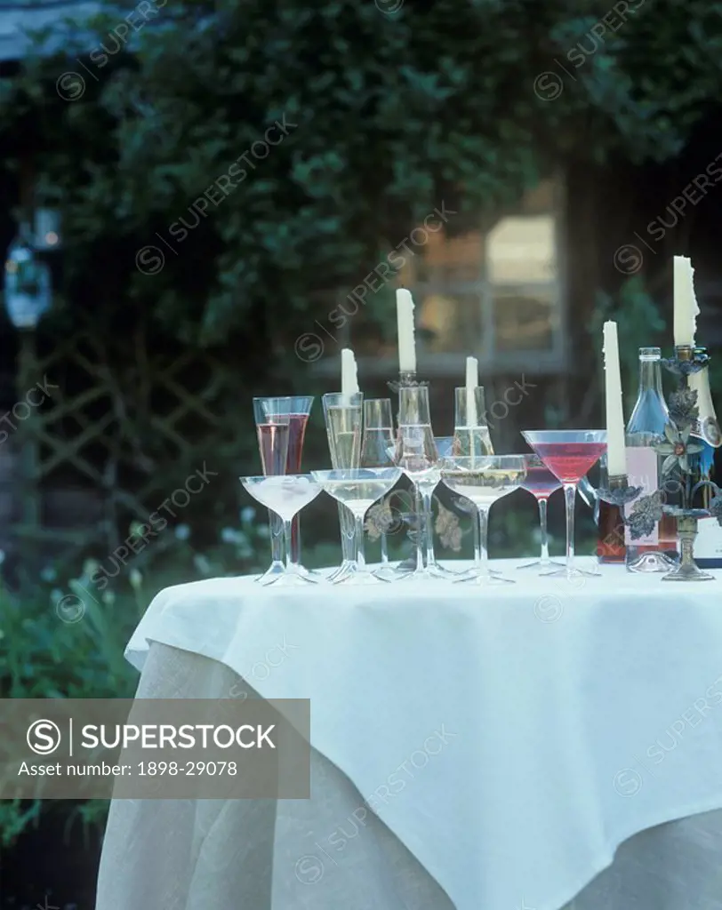 Garden table set with candles and drinks.