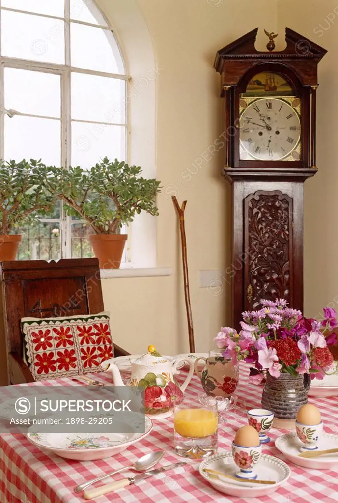 Table laid for breakfast with long case clock in the corner