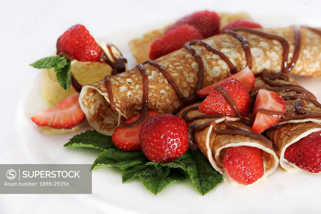 A detail of dessert pancakes with strawberries and chocolate sauce