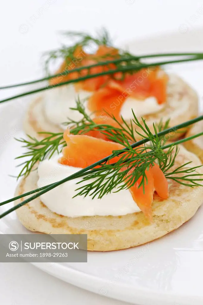 A detail of buttermilk pancakes with salmon and soured cream, garnished with dill