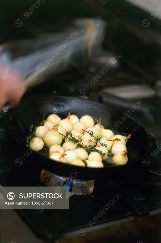 Small pickling onions frying in pan