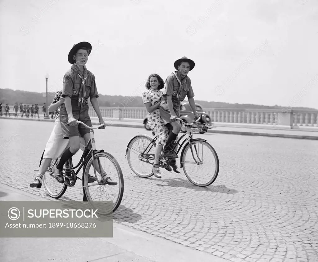 Two Boy Scouts giving their girlfriends a ride on their bicycles across the Arlington Bridge circa 1937.