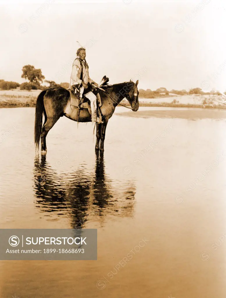 Edward S. Curits Native American Indians - Cheyenne man on horseback in shallow water circa 1927.