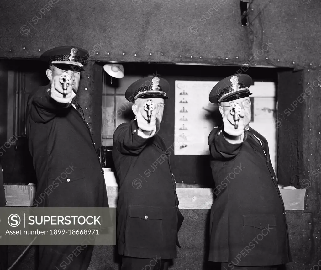 Three police officers pointing their guns (revolvers) at the photographer circa 1936.