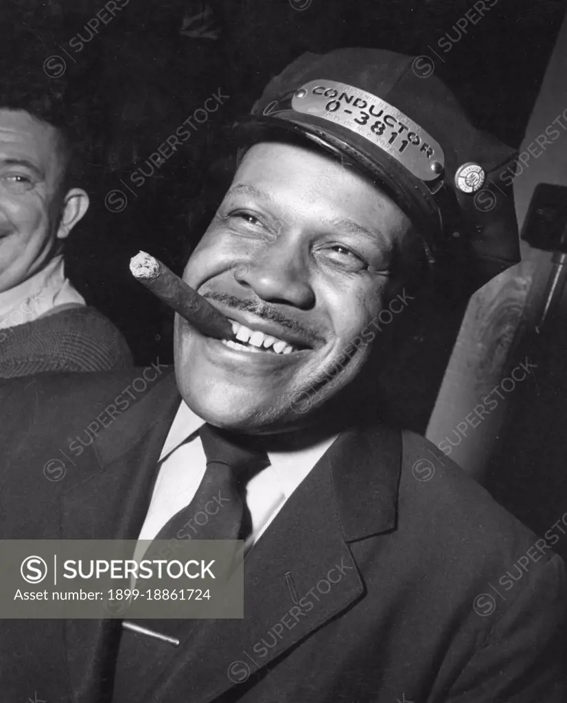 A New York Subway conductor enjoys a cigar in a crew recreation room. The wage of a first year conductor is $1.10 per hour for a forty-eight hour week. On the side of his cap he wears his union button signifying membership in the Transport Workers Union of the Congress of Industrial Organizations (CIO), New York, NY, 1948. (Photo by United States Information Agency/GG Vintage Images) 