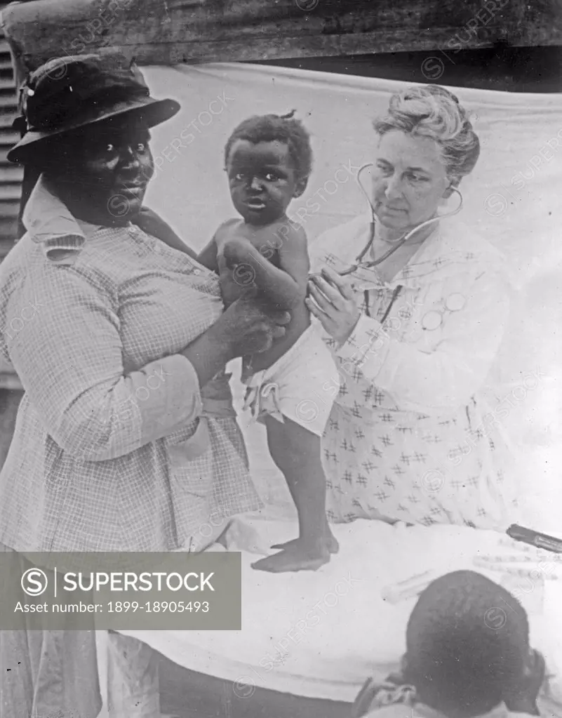 African American woman has her toddler examined by a doctor or nurse ca.  between 1918 and 1928.
