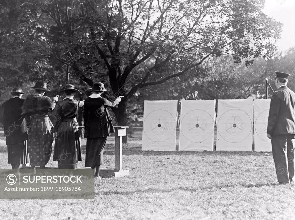 Four policewomen shooting at targets, as a policeman watches ca. 1909.