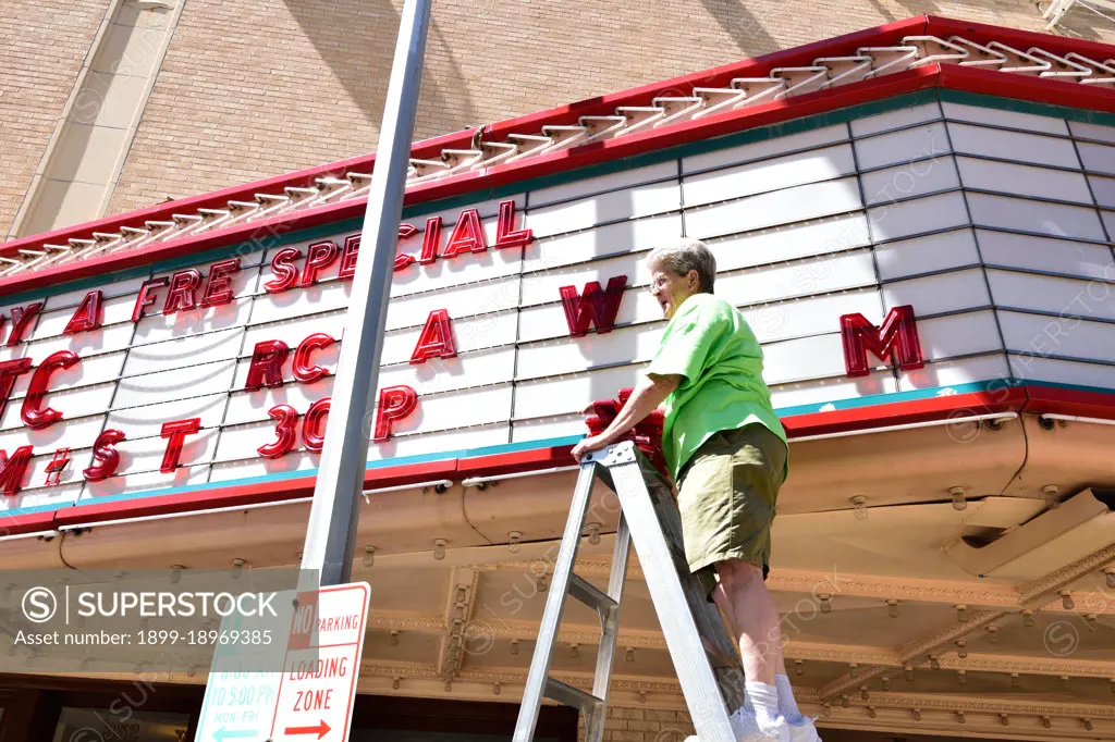 A woman placing letters on the marquee of the Paramount Movie Theater in Abilene, TX.