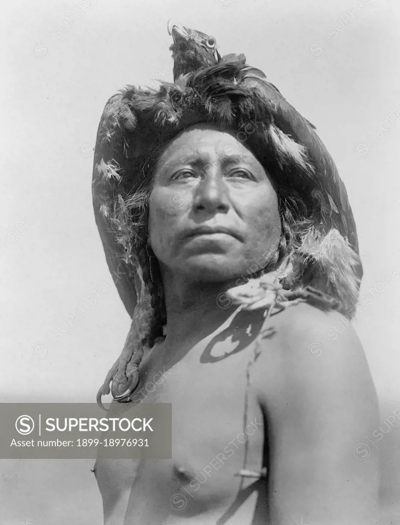 Edward S. Curtis Native American Indians - Apsaroke shaman, head-and-shoulders portrait, facing front, wearing eagle headdress ca. 1908. 