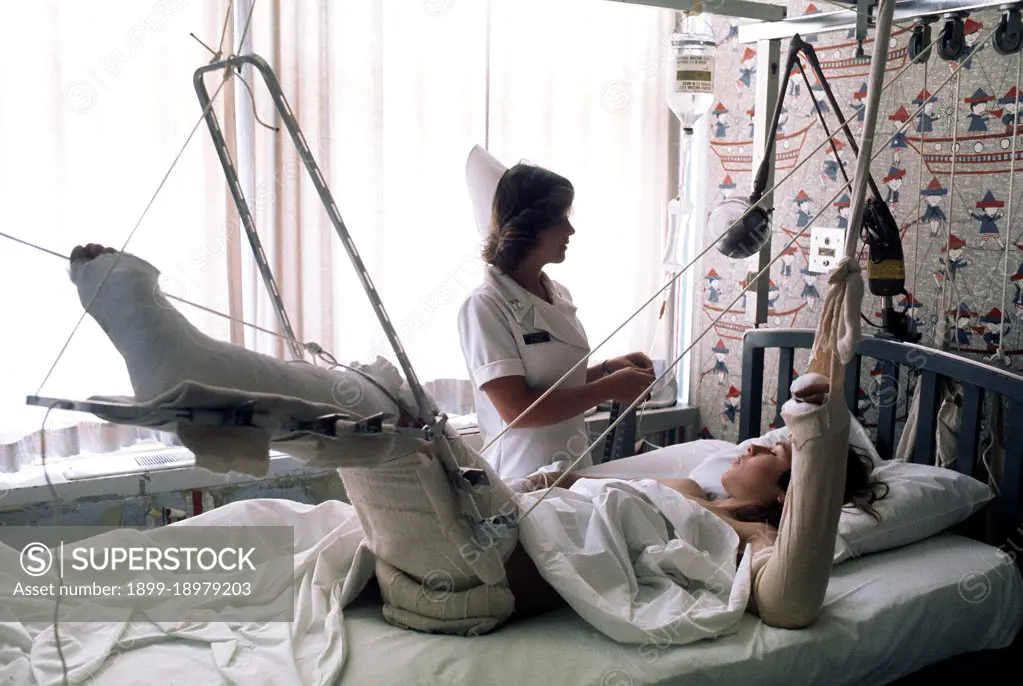 1976 - A nurse adjusts the intravenous feeding line on a patient. 