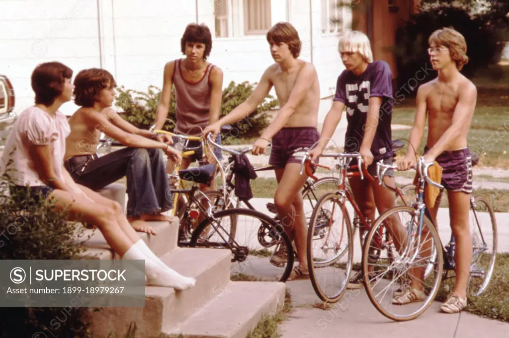 Teens on bicycles talk in front of a home in New Ulm, MN in 1973. 