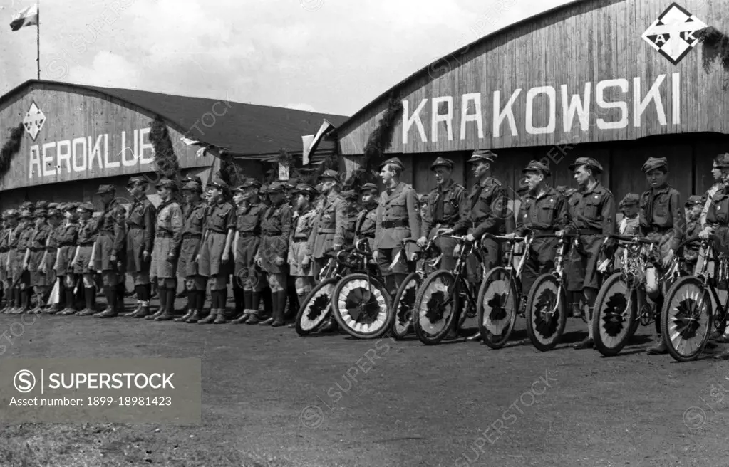 Cyclists with decorated bikes in front of the hangar of the Krakow Aeroclub at the Rakowicki airport ca. May 1, 1937. 