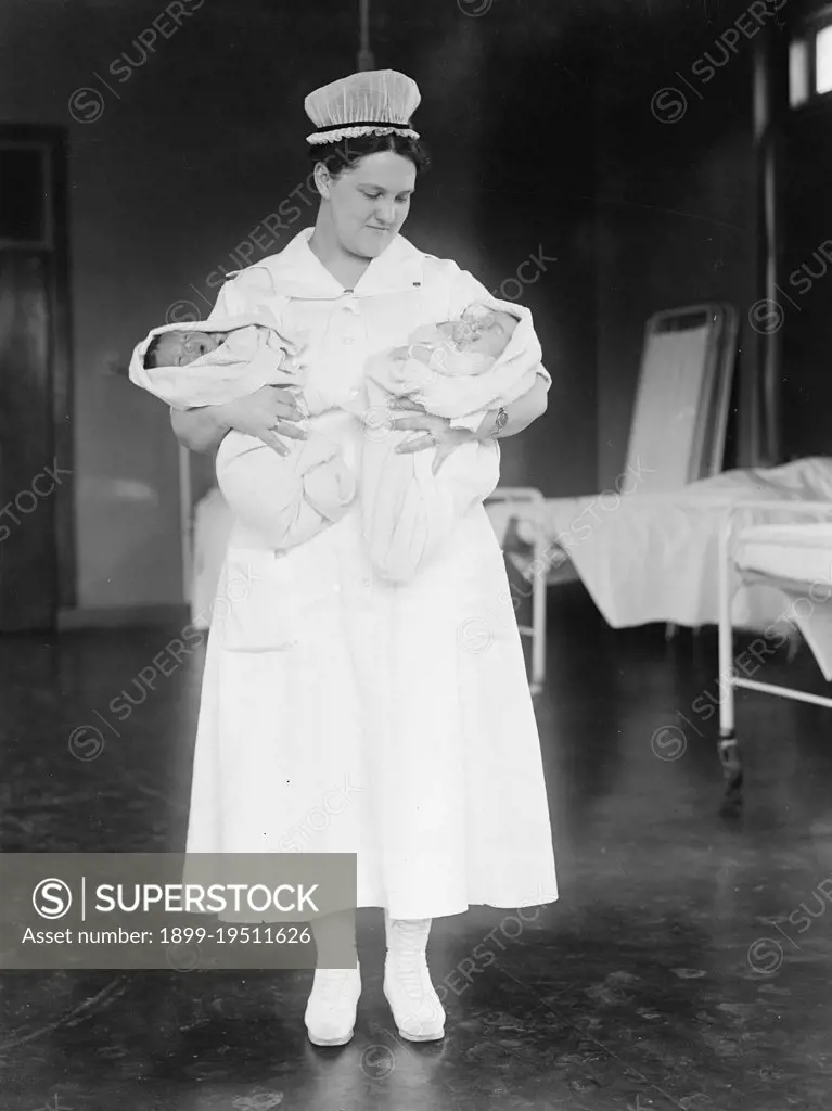 Nurse holding two babies ca. 1916-1919
