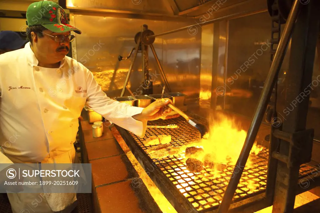 chef cooks steak, ribs and fish on the oak grill of the Hitching Post Restaurant, Buellton, Santa Ynez Valley, California, United States of America