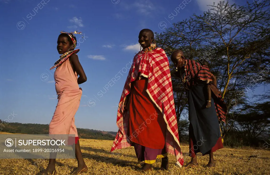 Maasai women, one carrying baby on back, and a child Narotian, Masai Mara, Kenya