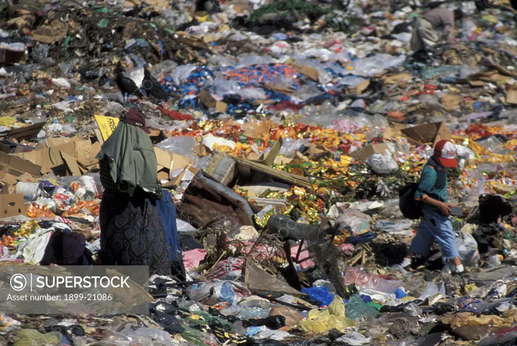 Waste scavengers at rubbish dump, Salvador. Mother and son at City dump, Apopa, El Salvador, collecting useful items in the rubbish. Garbage collectors, make money by selling the items.