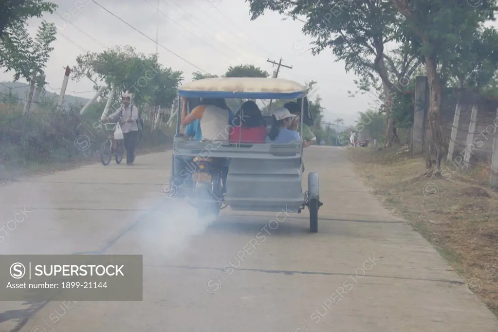 A smoke belching tricycle, climbs a steep hill, Palawan Island, Philippines . 
