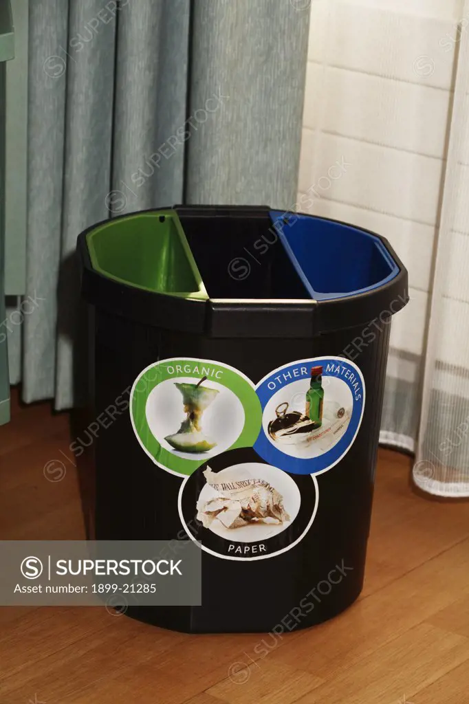 Hotel room recycling bin with separate colour-coded compartments for organic, paper and other waste materials, Finland. 