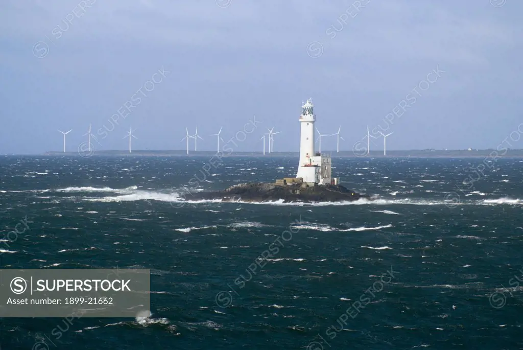 Tuskar lighthouse and Carnsore Point windfarm, Ireland. Lighthouse on Tuskar (aka. Tusker) rock in Irish Sea nr. Rosslare, Carnsore Point windfarm (14 turbines) - Ireland's most south-easterly point in background, Wexford, Republic of Ireland, Europe.
