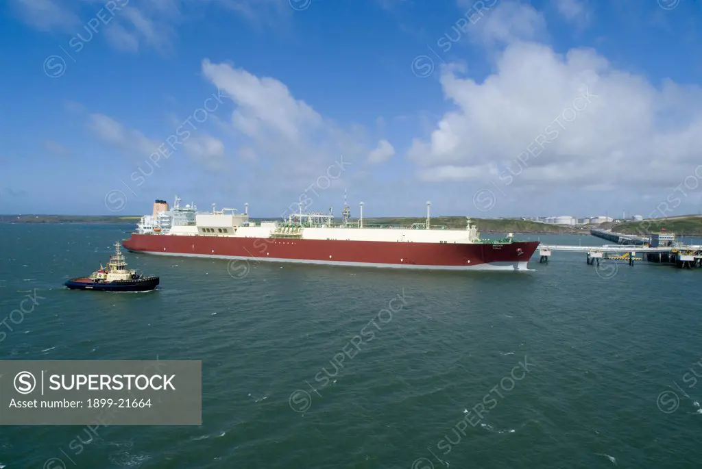 The 'Mozah', world's largest LNG tanker, United Kingdom. The 'mozah', world's largest LNG (= liquefied natural gas) tanker - total capacity 266,000 m3, shipping qatargas to Europe, docked at South Hook storage & regasification plant (Europe's largest LNG terminal), tugboat sailing past, Milford Haven, Pembrokeshire, Wales, UK, Europe.