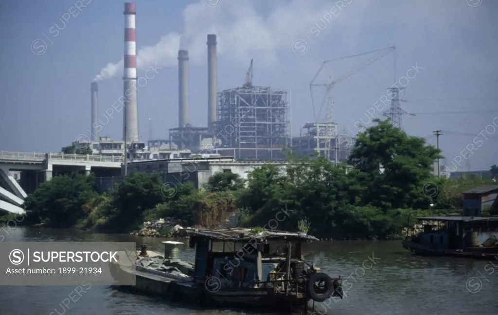 CHINA Jiangsu Province Transport. Boat travelling down the Grand Canal between Suzhou and Wuxi. Power station with smoke emitting from cooling towers and large industrial buildings under construction..  