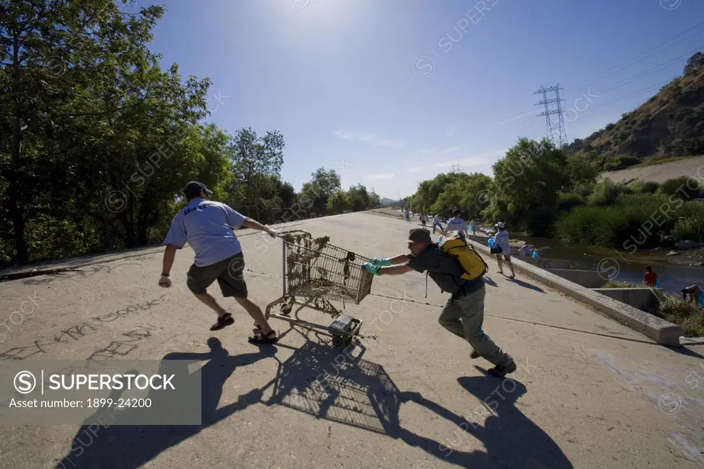Removing a shopping trolley from the Los Angeles River. FoLAR's annual 'La Gran Limpieza' clean up of the Los Angeles River. Bette Davis Picnic Area. Glendale Narrows. Los Angeles. 