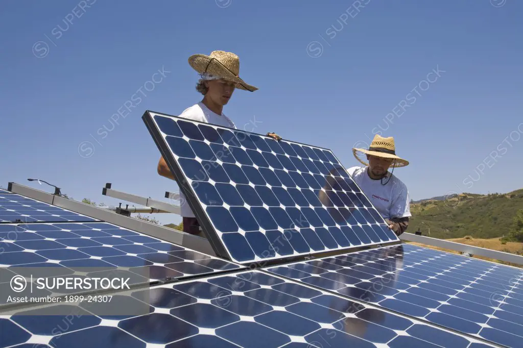 Green workers install a residential grid-tied solar array on a hillside in Malibu, California, USA. 