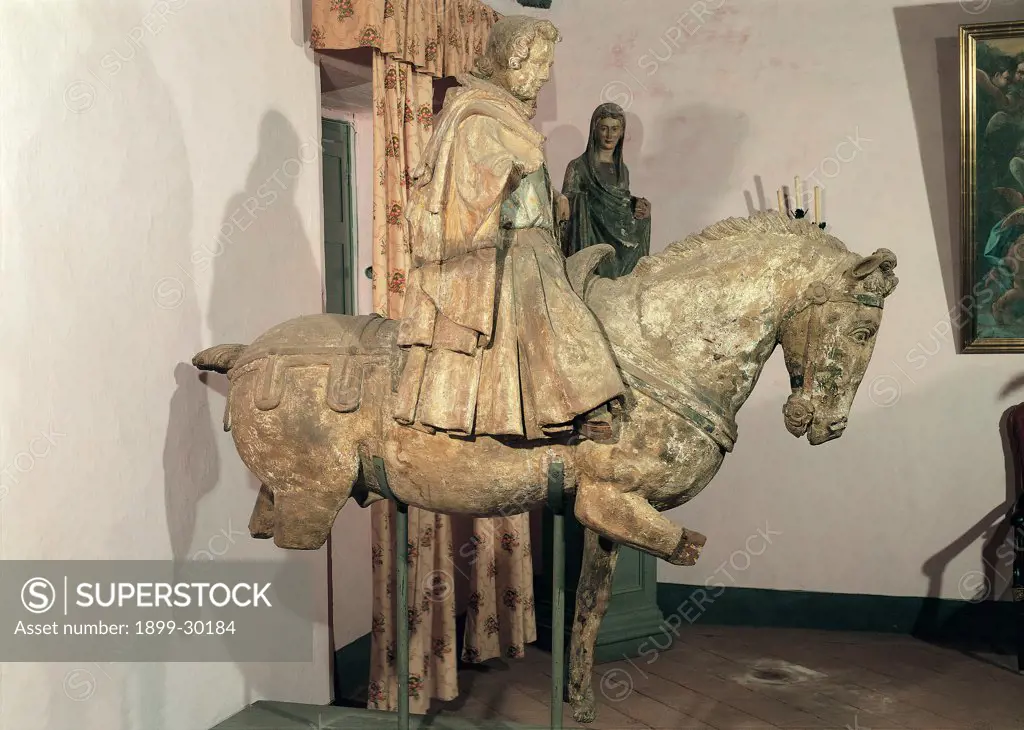 St Cassian, by Francesco di Valdambrino, 15th Century, wood carved and polychrome. Italy, Tuscany, Bagni di Lucca, Lucca, St Cassian Parish Church. Whole artwork. St Cassian man horse harness mantle: cloak habit wood carving.